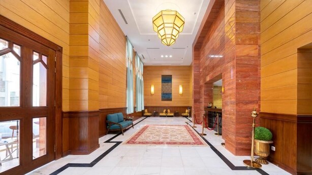 Eine großzügige Lobby mit Marmorboden, Holzvertäfelung, einer zentralen Sitzecke und einem Chandelier.