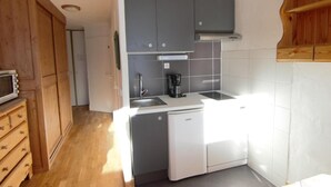 Una cocina compacta con armarios grises, un lavavajillas blanco y un mueble de madera con un microondas.