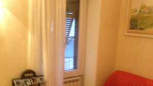 Ein kleines Wohnzimmer mit einem roten Sofa, einer Kaffeemaschine und einer Heizung.