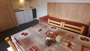 Um quarto pequeno e acolhedor, com uma cama de madeira, uma cozinha compacta e um banheiro pequeno.