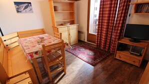 A cozy room with a wooden table and chairs, a small cabinet, a television, and a window with curtains. - 150m from ski slopes, 3rd floor, view ski slopes, balcony, 29m², Val Thorens (Val Thorens)
