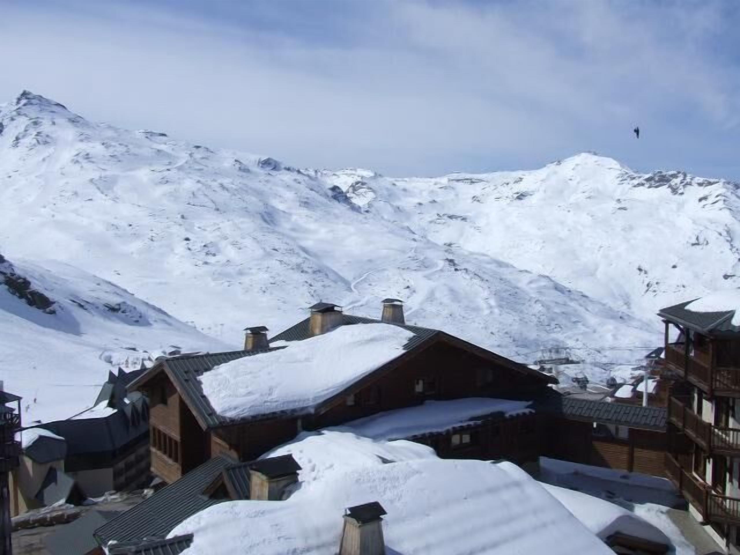 Ein verschneites Bergdorf mit traditionellen Holzhäusern und freiem Blick auf die umliegenden Gipfel.