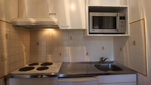 A compact kitchen with a gas stove, a microwave, and a sink.