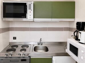 Una cocina equipada con microondas, estufa, fregadero y cafetera.
