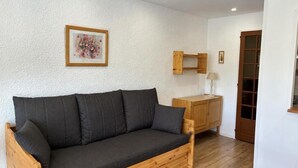 Un sofá de madera con cojines en una habitación con paredes blancas y suelo de madera.