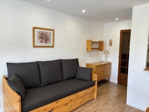 A wooden sofa with cushions in a room with white walls and a wooden floor.