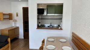 Una cocina compacta con comedor, muebles de madera y un mueble pequeño.