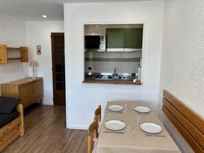 A compact kitchen with a dining area, wooden furniture, and a small cabinet.