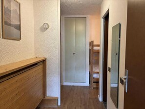 A hallway with a wooden bench, a door with a mirror, and a wardrobe.