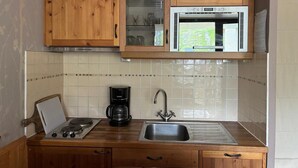 A kitchen with wooden cabinets, a microwave, a coffee maker, and a sink. - 200m from resort center, 2nd floor, balcony, tv, 21m², Val Thorens (Val Thorens)