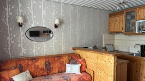 A compact living space with a sofa, a small kitchen area, and a wall-mounted light fixture. - 200m from resort center, 2nd floor, balcony, tv, 21m², Val Thorens (Val Thorens)