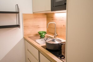 A compact kitchen with a sink, a green colander, and a pot on the stove. - 200m from ski slopes, 1st floor, balcony, tv, 37m², Val Thorens (Val Thorens)
