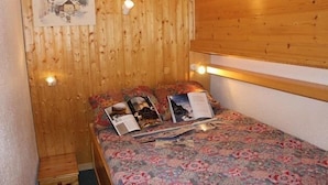 A wooden-paneled room with a bed, a small table, and a wall-mounted light fixture. - 200m from ski slopes, 1st floor, balcony, tv, 37m², Val Thorens (Val Thorens)