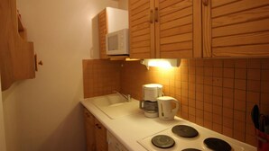 A compact kitchen with wooden cabinets, a microwave, a coffee maker, and a sink. - 200m from ski slopes, 1st floor, balcony, tv, 37m², Val Thorens (Val Thorens)