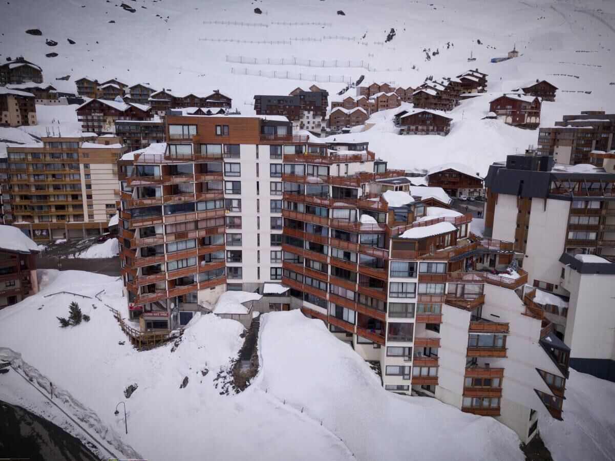 A multi-story hotel with balconies and a ski slope in the background.