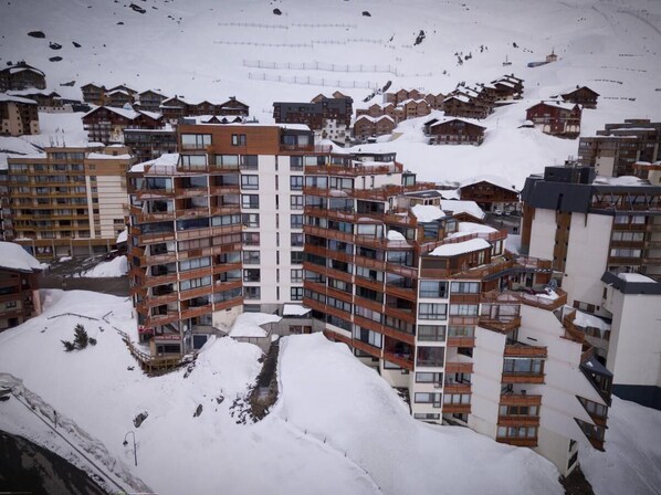 A multi-story hotel with balconies and a ski slope in the background.