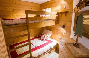 A bunk bed with a red and white quilt, a pillow, and a wooden ladder. - 200m from ski slopes, 2nd floor, tv, 35m², Val Thorens (Val Thorens)