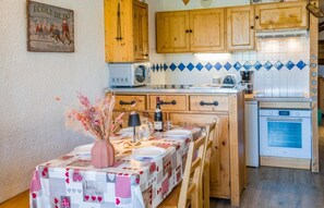 A kitchen with wooden cabinets, a microwave, and a stove. - 200m from ski slopes, 2nd floor, tv, 35m², Val Thorens (Val Thorens)