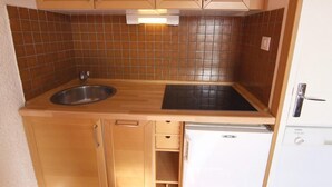 A compact kitchen with wooden cabinets, a stainless steel sink, a black countertop, and a built-in dishwasher. - 200m from ski slopes, 4th floor, tv, 18m², Val Thorens (Val Thorens)