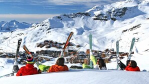 A group of people resting on a snowy slope with skis, overlooking a snow-covered mountain and a village below. - 200m from ski slopes, 4th floor, tv, 18m², Val Thorens (Val Thorens)