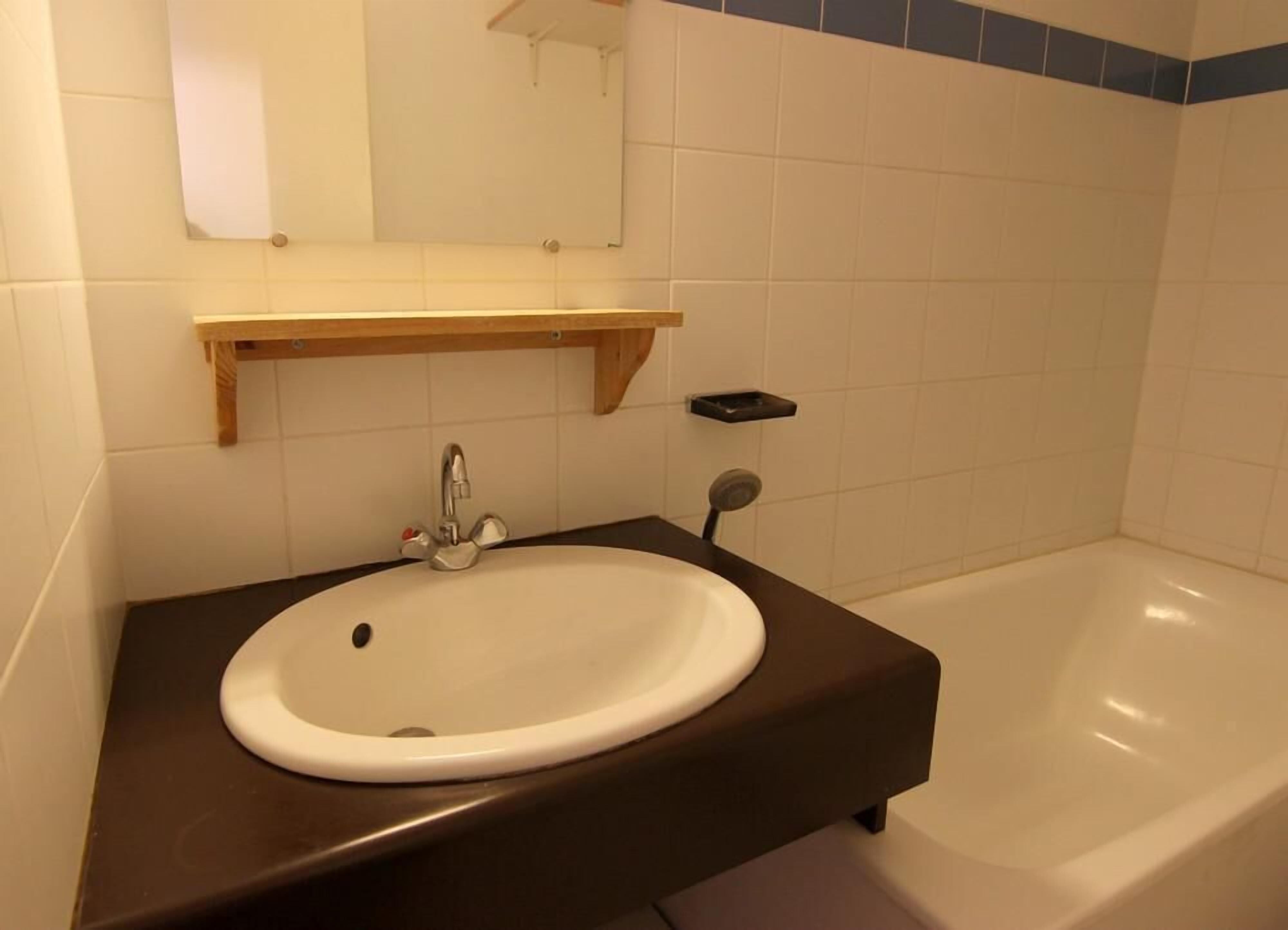 A bathroom with a white sink, a mirror above it, and a bathtub.