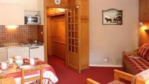 Eine kompakte Küche mit Mikrowelle, Herd und einem Essbereich mit Tisch und Stühlen.