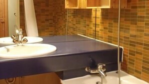 Ein Badezimmer mit einem Doppelwaschbecken, einer Dusche, Holzschränken und einer gefliesten Rückwand.