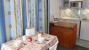 Een kleine kitchenette met een magnetron, spoelbak en koffiezetapparaat. Er staat een tafel met een paar spullen op, waaronder een broodrooster, kopjes en een potje jam.