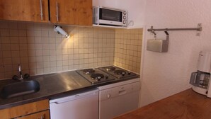 Kompakti keittiö, jossa on mikroaaltouuni, liesi ja astianpesukone.