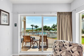 A room with a large sliding glass door leading to a balcony with a pool view.