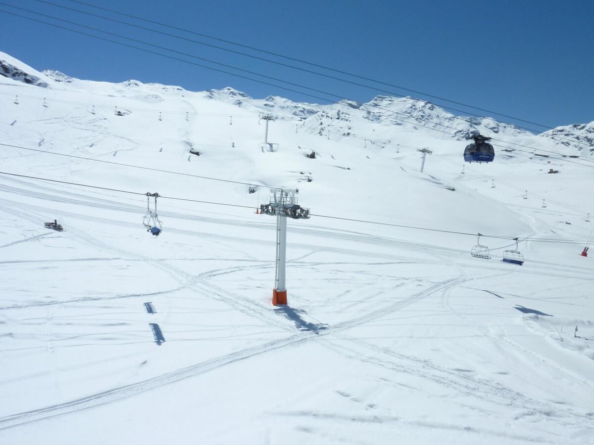 A ski lift chair moving along a snowy mountain slope.