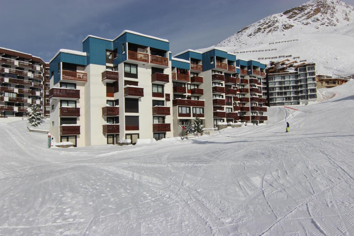 A multi-story hotel with balconies, located in a snowy mountainous area.