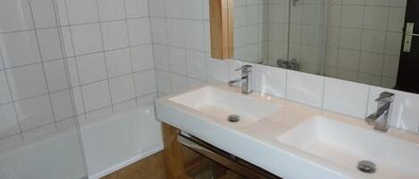 A bathroom with two sinks, a mirror, and a bathtub.