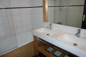 Casa de banho com duas pias, espelho e banheira.