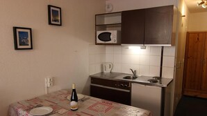 Eine kompakte Küche mit Mikrowelle, Wasserkocher und einem Esstisch für zwei Personen.