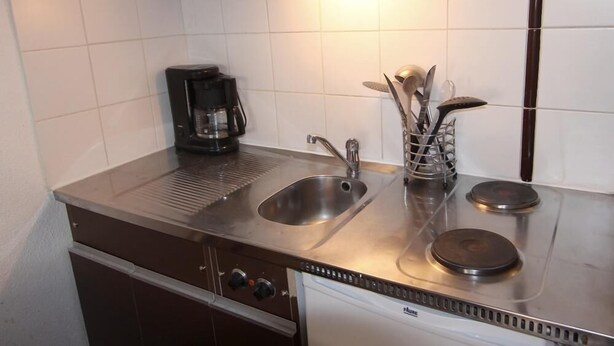 Eine kleine Küche mit Mikrowelle, Kaffeemaschine, Spüle und Herd.