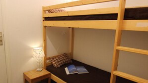 Ein Schlafzimmer mit Etagenbetten, einem kleinen Nachttisch und einer Lampe.