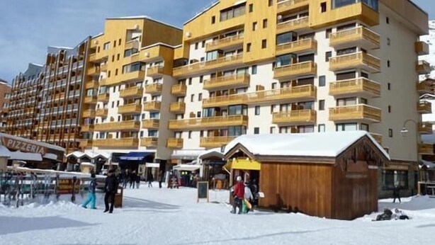 Ein mehrstöckiges Hotel mit Balkonen, einem Skigebiet und einem Holzbauten.