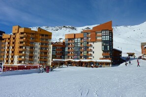 Un moderno complejo de esquí con edificios de varios pisos, remontes y un paisaje nevado.