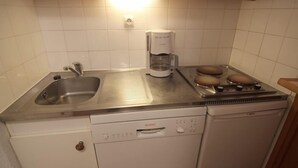 Una cocina compacta con lavavajillas Bosch, cafetera y estufa.