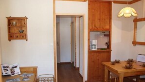 Una habitación acogedora con una cama de madera, un pequeño armario de madera, una mesa de comedor con sillas y una lámpara colgante.