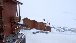 Un edificio in legno con balconi e terreno coperto di neve.