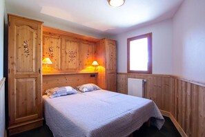 Une chambre à coucher avec une tête de lit en bois, deux lampes de chevet, un radiateur et une fenêtre.
