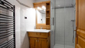 A bathroom with a wooden vanity, a sink, a mirror, a shower enclosure, and a towel rack. - 3rd floor, balcony, tv, ski locker, 56m², Val Thorens (Val Thorens)