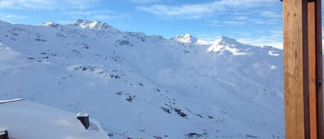 A snowy mountain landscape with a wooden building and a ski resort in the foreground.