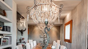 A long wooden dining table with white upholstered chairs, a decorative metal sculpture centerpiece, and a large chandelier. - Superior room with balcony overlooking the canal port of Cesenatico (Cesenatico)