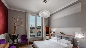 A modern bedroom with a large bed, a wooden floor, a view of the city, and a chandelier. - Superior room with balcony overlooking the canal port of Cesenatico (Cesenatico)
