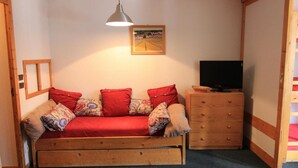 A cozy room with a wooden sofa, a wooden dresser, a television, and a framed picture on the wall. - 50m from ski slopes, 2nd floor, balcony, tv, 35m², Val Thorens (Val Thorens)