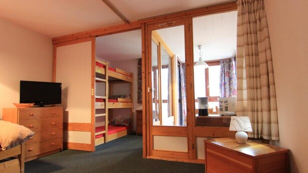 A bedroom with a bunk bed, a wooden dresser, a desk, and a television. - 50m from ski slopes, 2nd floor, balcony, tv, 35m², Val Thorens (Val Thorens)