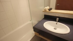A bathroom with a white bathtub, a white sink, and a wooden shelf with decorative items. - 50m from ski slopes, 2nd floor, balcony, tv, 35m², Val Thorens (Val Thorens)